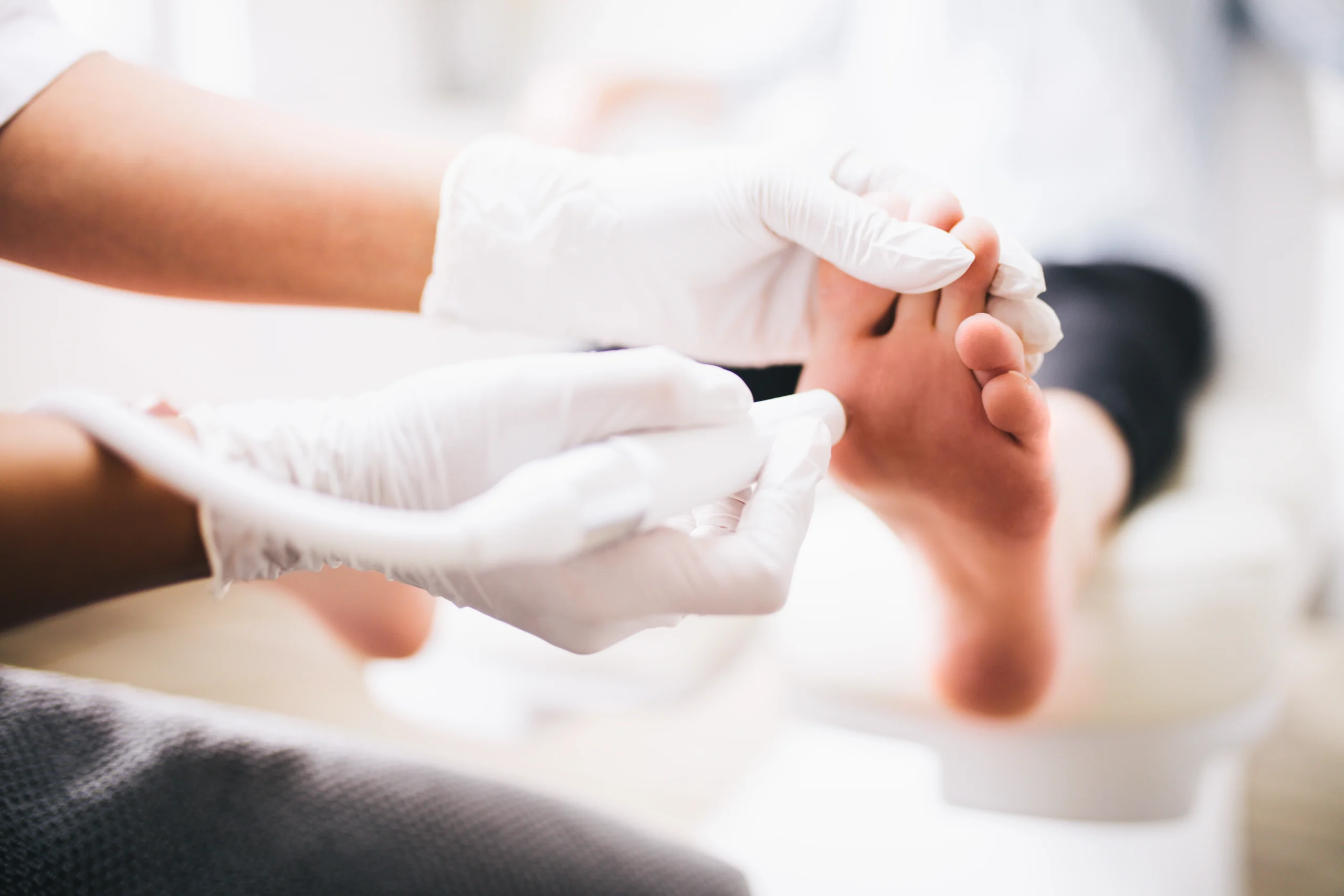 Podiatrist administering localized shockwave therapy or cold laser treatment to the bottom of a patient's foot.