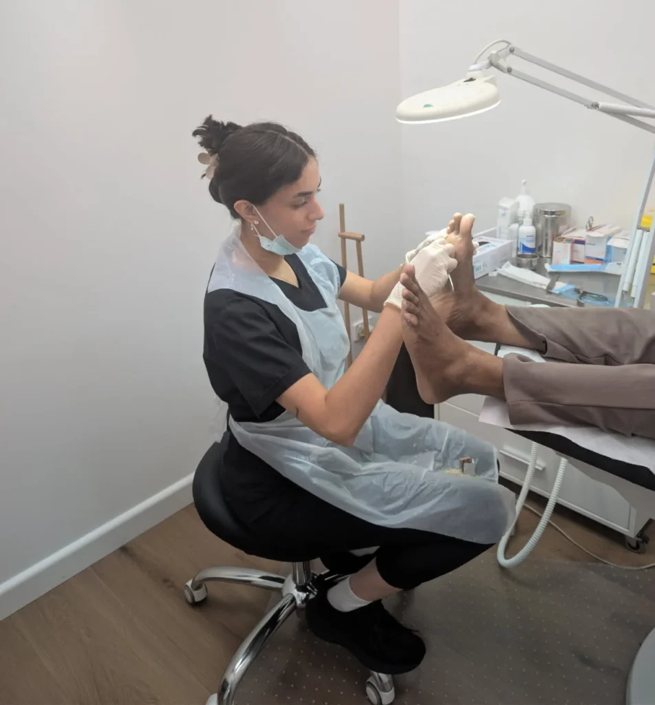 Podiatrist conducting a foot checkup and treatment in a clean, modern clinic setting.