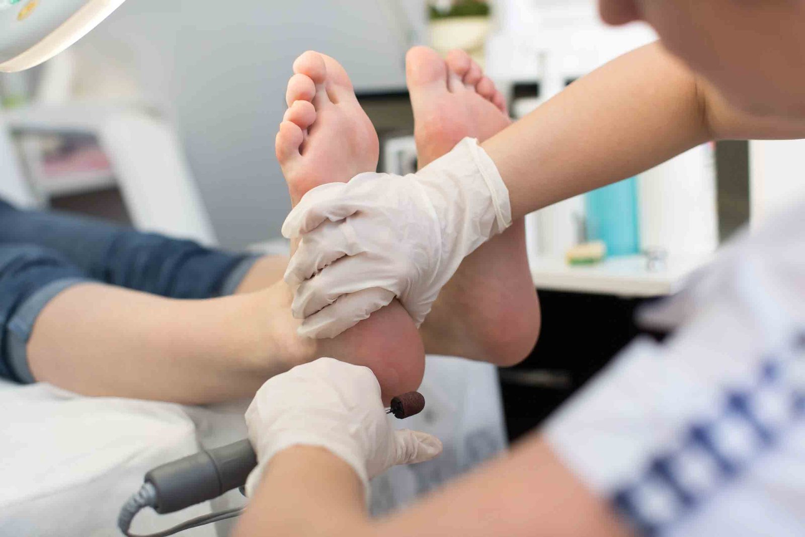 Podiatrist administering localized photobiomodulation or laser therapy to the bottom of a patient's foot.